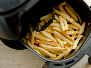 A close up of an air fryer which contains fries