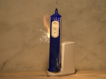 An electric toothbrush catches fire and sparks on its charging dock.