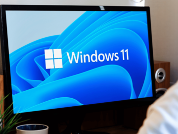 A man looking at s Windows 11 logo on a computer screen
